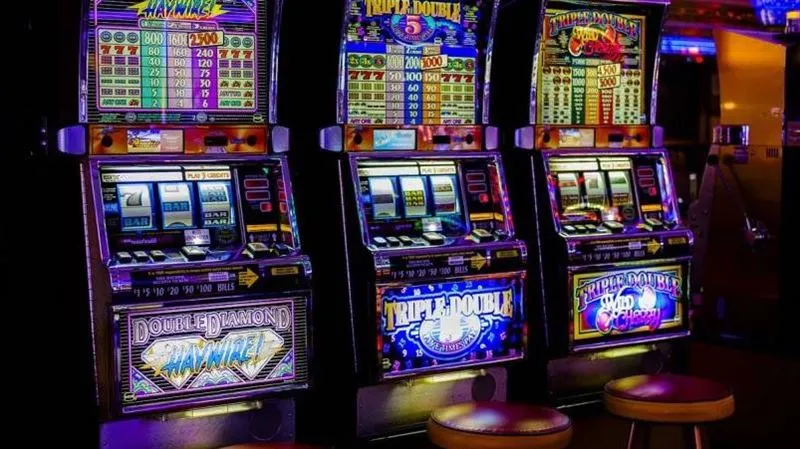 娛樂城內部三台經典老虎機遊戲機台，展示彩燈與下注介面設計